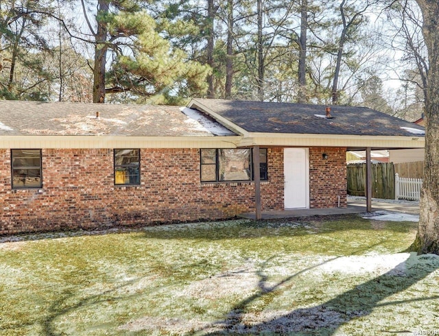 back of property featuring a yard, fence, a carport, and brick siding