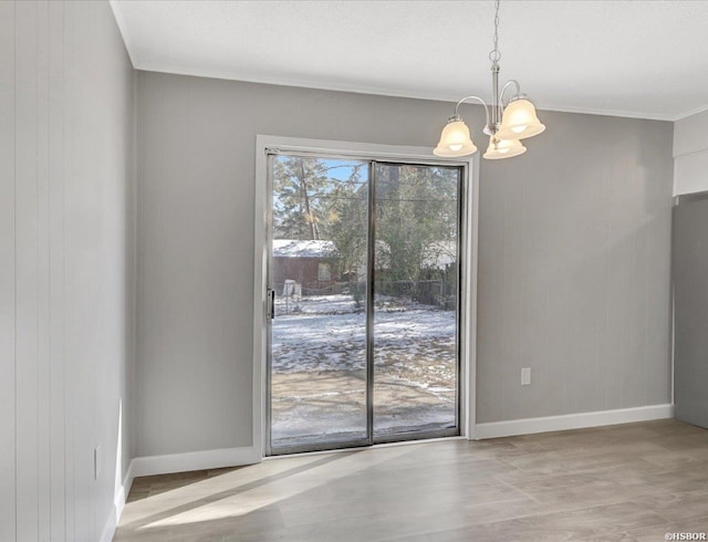 unfurnished dining area featuring a chandelier, crown molding, and baseboards