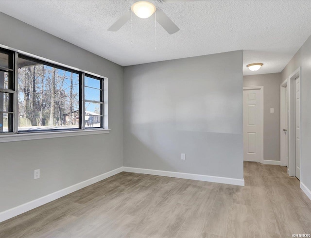 empty room featuring light wood finished floors, ceiling fan, baseboards, and a textured ceiling