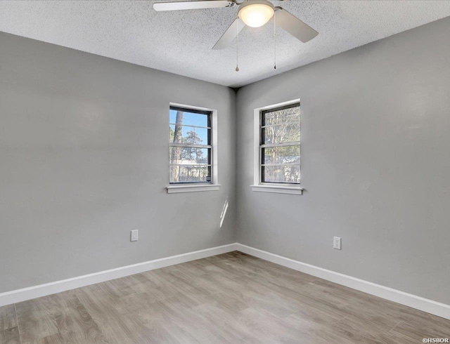 unfurnished room featuring ceiling fan, light wood finished floors, baseboards, and a textured ceiling