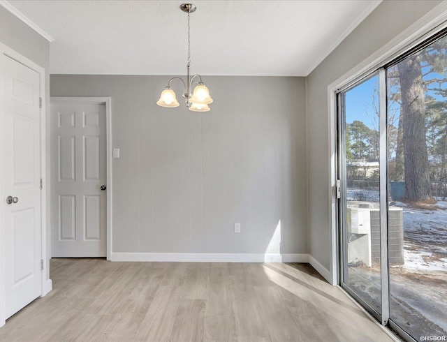 unfurnished dining area with crown molding, baseboards, a notable chandelier, and light wood finished floors