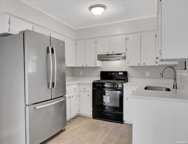 kitchen with black range with gas cooktop, light countertops, a sink, and freestanding refrigerator