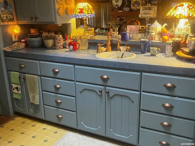 kitchen with dark countertops, light floors, a sink, and gray cabinetry