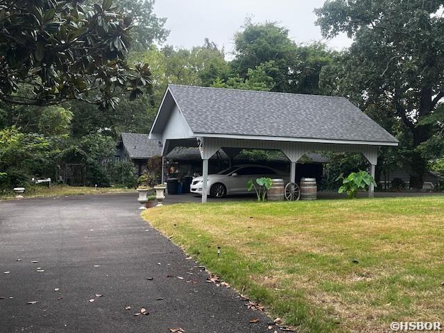 view of community featuring driveway, a carport, and a yard