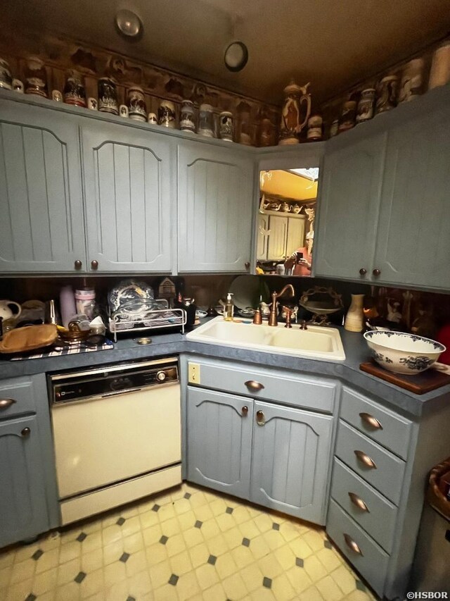 kitchen with dishwasher, dark countertops, gray cabinets, light floors, and a sink