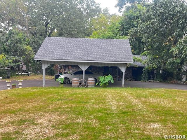 view of community with driveway, a carport, and a yard