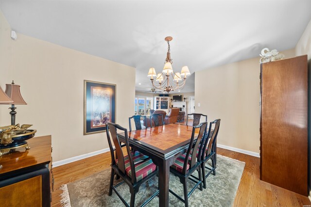 dining area featuring an inviting chandelier, baseboards, and light wood finished floors