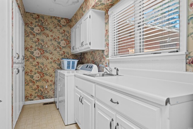 laundry room with cabinet space, washing machine and dryer, a sink, baseboards, and wallpapered walls