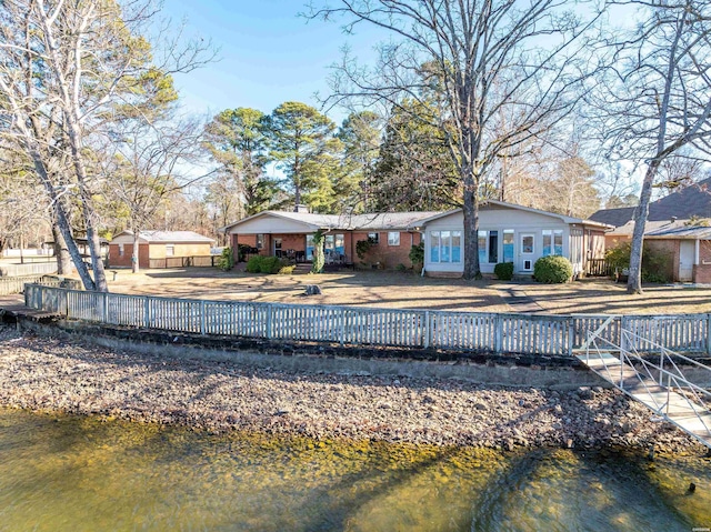 rear view of house featuring a water view, a chimney, and fence