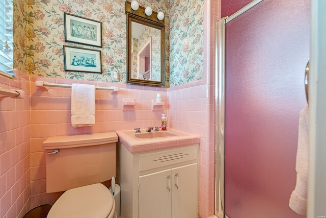 bathroom featuring a stall shower, a wainscoted wall, and wallpapered walls