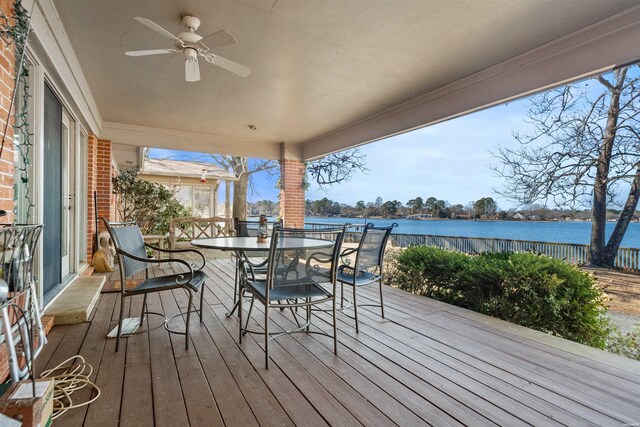 wooden terrace featuring outdoor dining area, a water view, and a ceiling fan