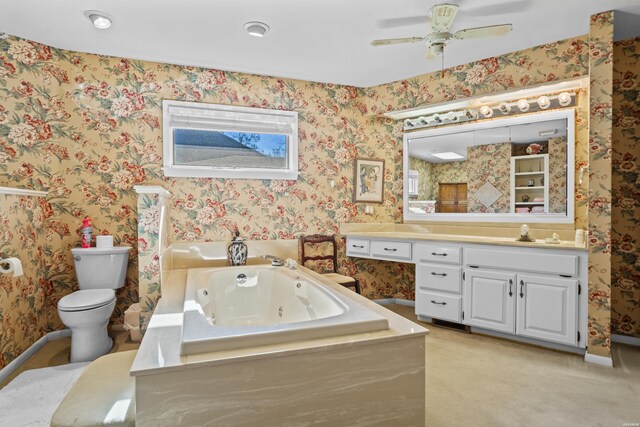 full bath featuring toilet, ceiling fan, vanity, a whirlpool tub, and wallpapered walls