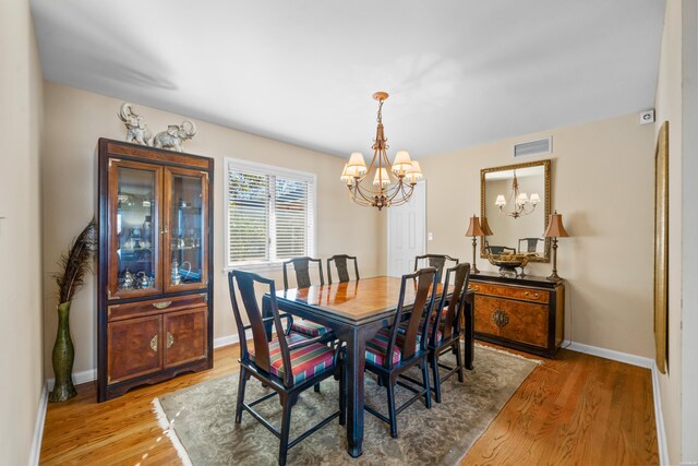 dining room with baseboards, wood finished floors, and an inviting chandelier