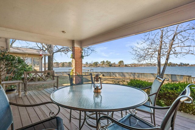 wooden deck with a water view and outdoor dining area