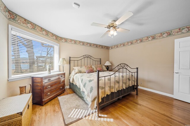 bedroom with light wood finished floors, baseboards, and a ceiling fan