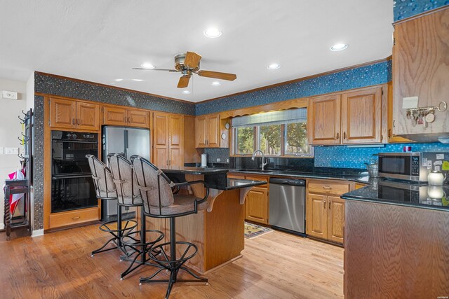 kitchen featuring a center island, a breakfast bar, stainless steel appliances, light wood-style flooring, and a sink