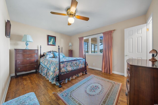 bedroom with ceiling fan, baseboards, and wood finished floors