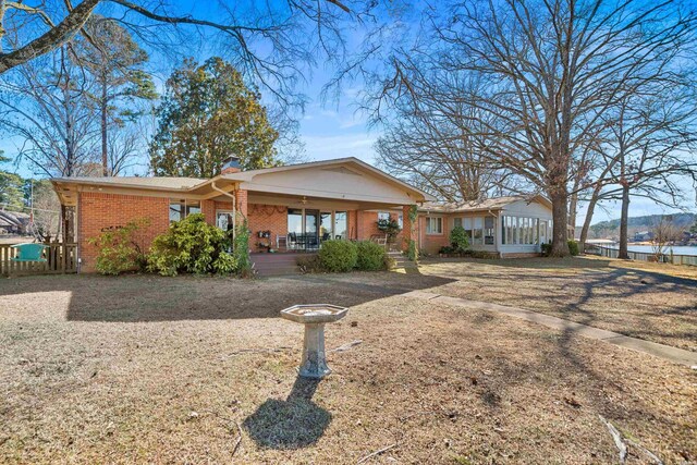 ranch-style house featuring covered porch, brick siding, and a chimney