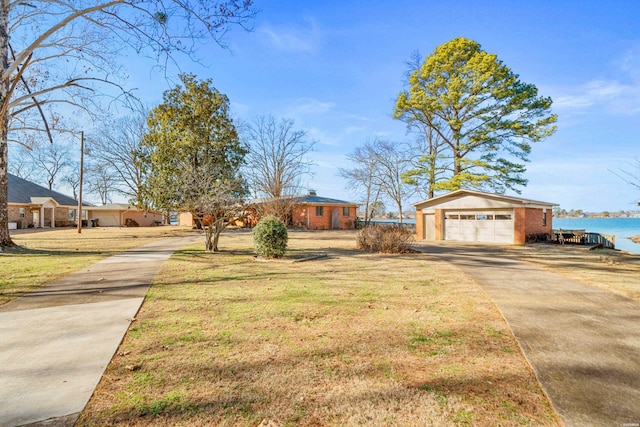 view of front of property featuring a water view, driveway, a garage, and a front yard