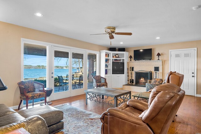 living room featuring ceiling fan, recessed lighting, a fireplace, and light wood-style floors