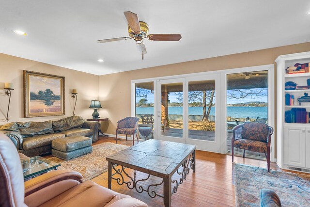 living area featuring light wood-style flooring, recessed lighting, a water view, a ceiling fan, and baseboards