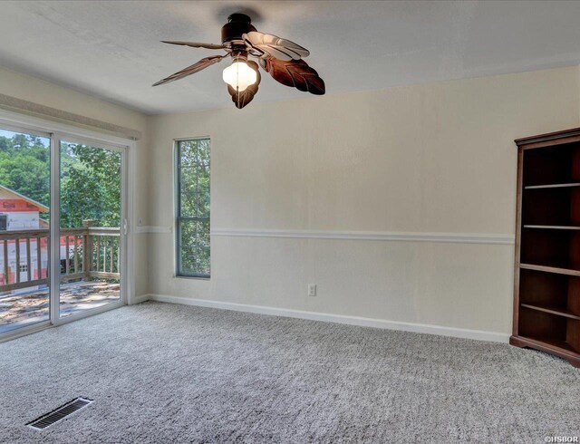 carpeted empty room with baseboards, visible vents, and a ceiling fan