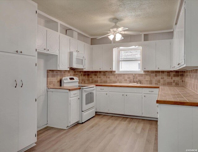 kitchen with white appliances, tile counters, white cabinets, and a sink