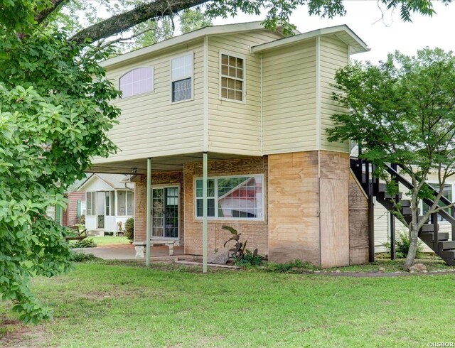 view of front facade featuring brick siding, a ceiling fan, a front yard, stairs, and a patio area