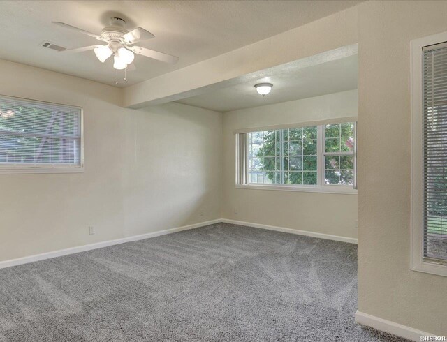 carpeted empty room with ceiling fan, visible vents, and baseboards