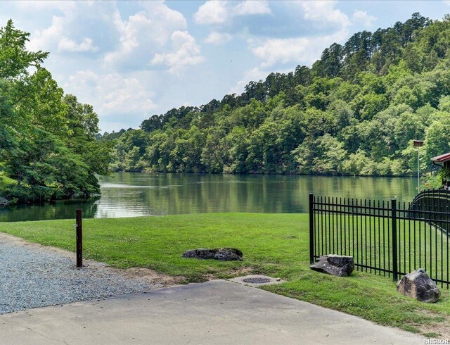 property view of water featuring fence and a view of trees