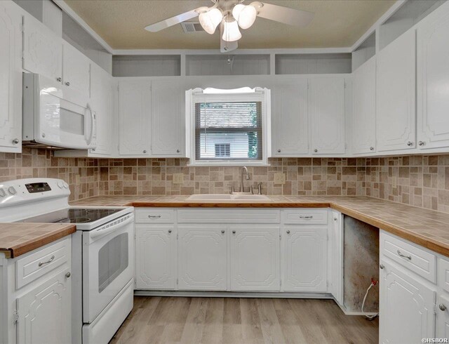 kitchen featuring white appliances, tasteful backsplash, light wood finished floors, white cabinetry, and a sink