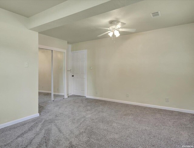 carpeted spare room featuring visible vents, ceiling fan, and baseboards