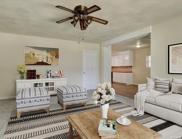 living area with a textured ceiling, ceiling fan, and baseboards