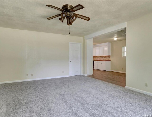 unfurnished living room featuring carpet floors, ceiling fan, baseboards, and a textured ceiling