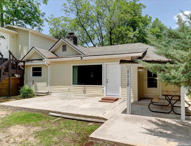 back of house with entry steps, a chimney, and a patio