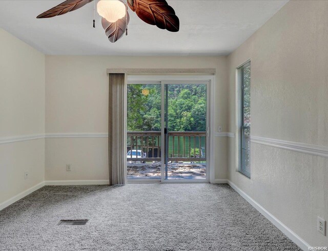 carpeted empty room with a ceiling fan, visible vents, and baseboards