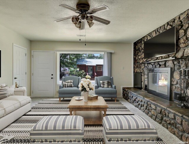 carpeted living area featuring a textured ceiling, ceiling fan, a fireplace, visible vents, and baseboards