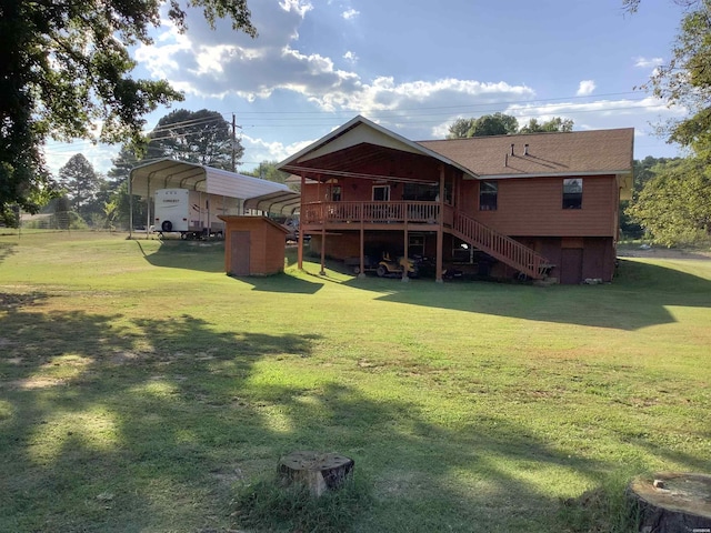 rear view of property with a detached carport, stairway, a shingled roof, a deck, and a lawn