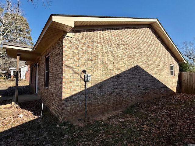 view of property exterior featuring brick siding and fence