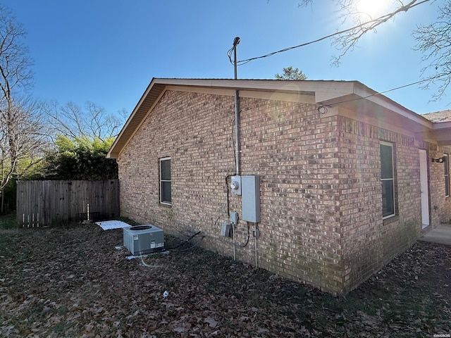 view of home's exterior featuring central AC, brick siding, and fence