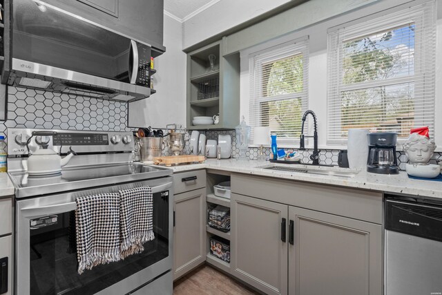 kitchen with tasteful backsplash, stainless steel appliances, a sink, and gray cabinetry