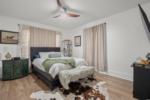 bedroom featuring light wood-style flooring, baseboards, and ceiling fan