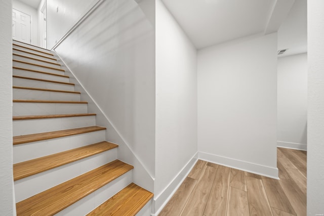 staircase with baseboards and wood finished floors