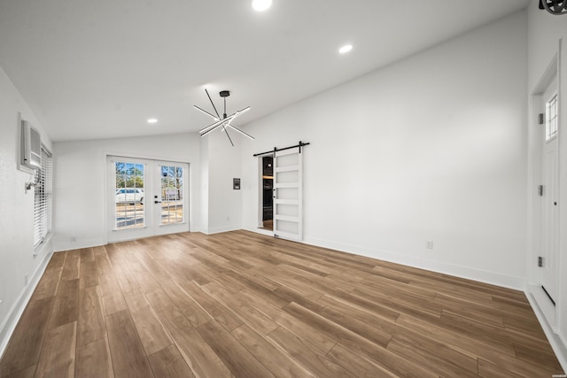 unfurnished living room featuring recessed lighting, wood finished floors, vaulted ceiling, and a barn door