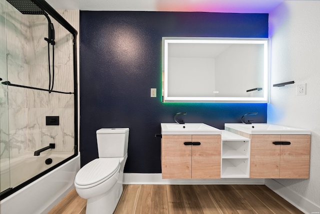 bathroom featuring enclosed tub / shower combo, wood finished floors, vanity, and baseboards