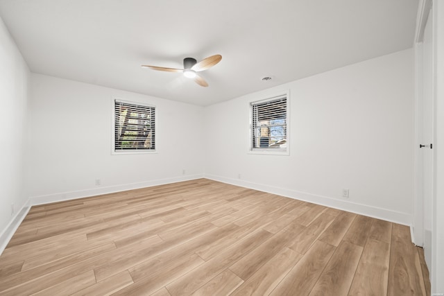 spare room featuring ceiling fan, baseboards, and light wood-style floors