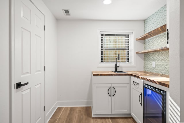 kitchen with open shelves, wood finished floors, butcher block countertops, beverage cooler, and baseboards