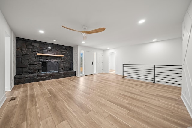 unfurnished living room with recessed lighting, visible vents, wood finished floors, and a stone fireplace