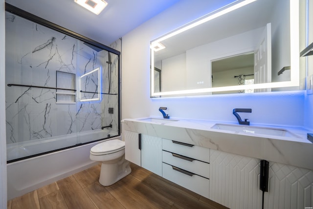 bathroom featuring toilet, enclosed tub / shower combo, a sink, and wood finished floors