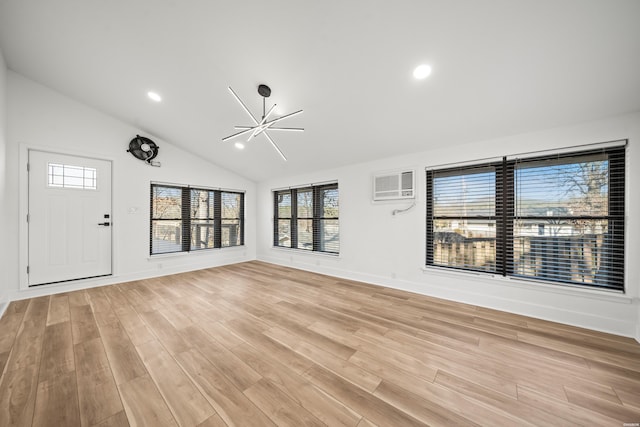 unfurnished living room featuring light wood finished floors, baseboards, vaulted ceiling, an AC wall unit, and recessed lighting